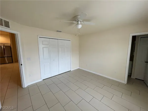 an empty room with closet and a chandelier fan
