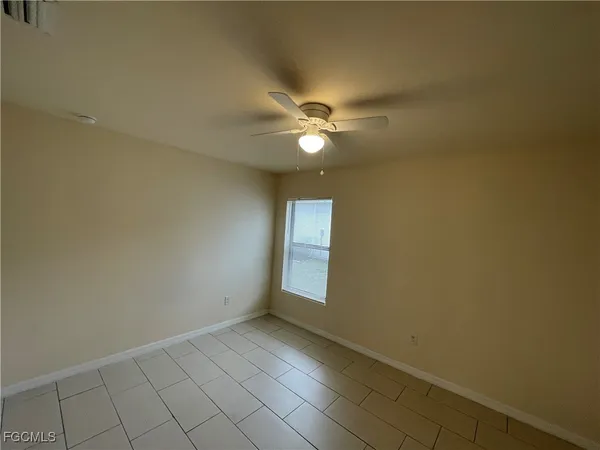 a view of an empty room with chandelier fan and fire place