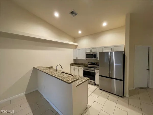 a kitchen with granite countertop a refrigerator and a stove top oven