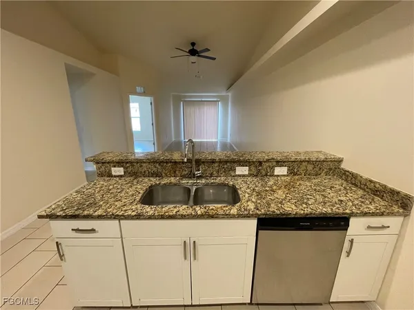 a kitchen with granite countertop a sink and white cabinets