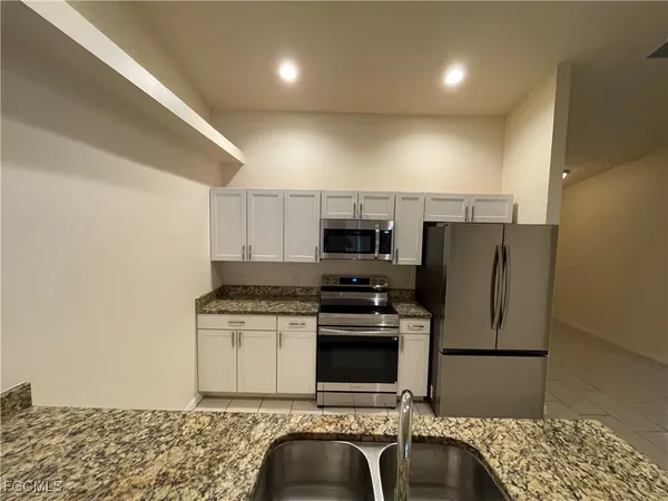a kitchen with stainless steel appliances granite countertop a refrigerator sink and stove