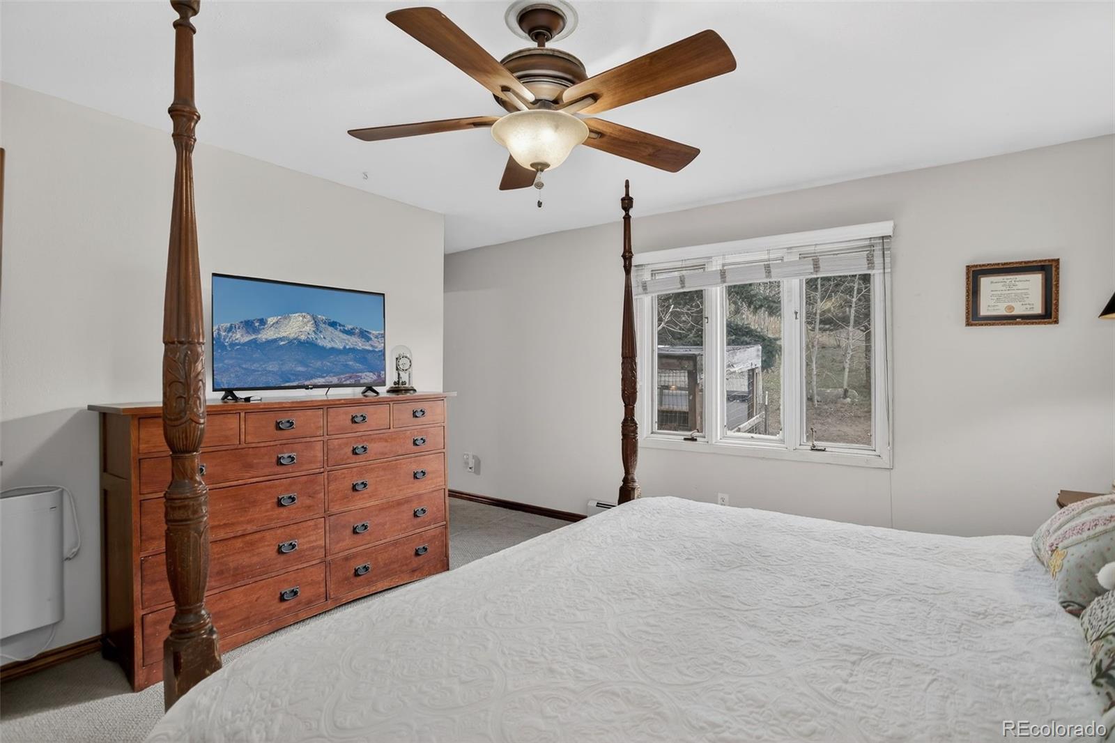 12699 South Foxton Road Conifer, CO 80433 - Photo 14 of 40 a bedroom with a bed and a chandelier