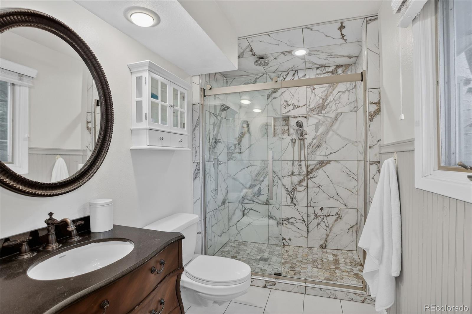 12699 South Foxton Road Conifer, CO 80433 - Photo 16 of 40 a bathroom with a sink toilet a mirror and shower