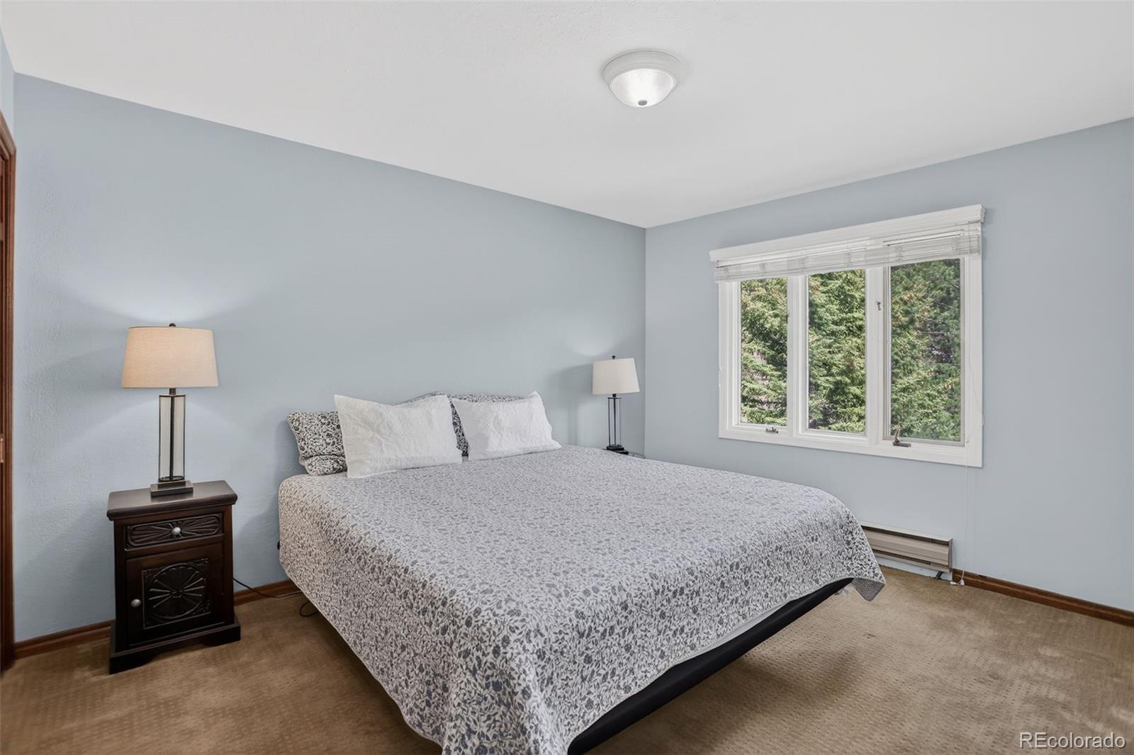 12699 South Foxton Road Conifer, CO 80433 - Photo 18 of 40 a bedroom with a bed and a lamp