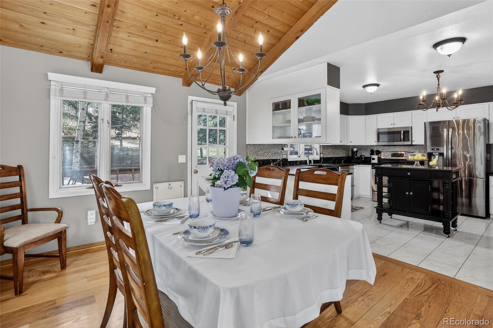 12699 South Foxton Road Conifer, CO 80433 - Photo 5 of 40 a kitchen with stainless steel appliances kitchen island granite countertop a stove a sink a dining table and chairs with wooden floor
