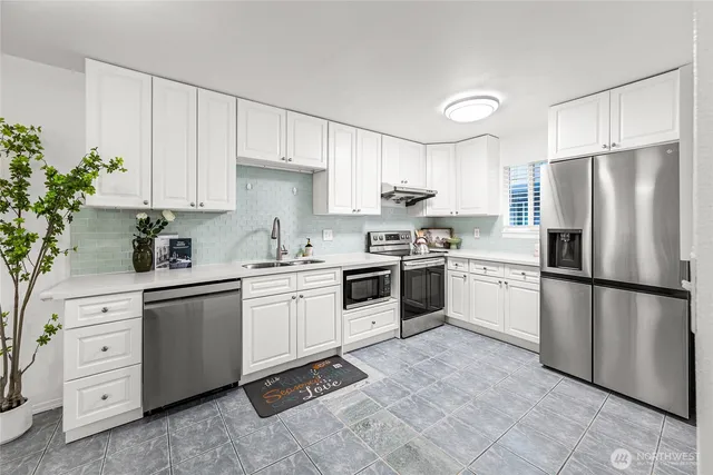 a kitchen with white cabinets stainless steel appliances and a potted plant