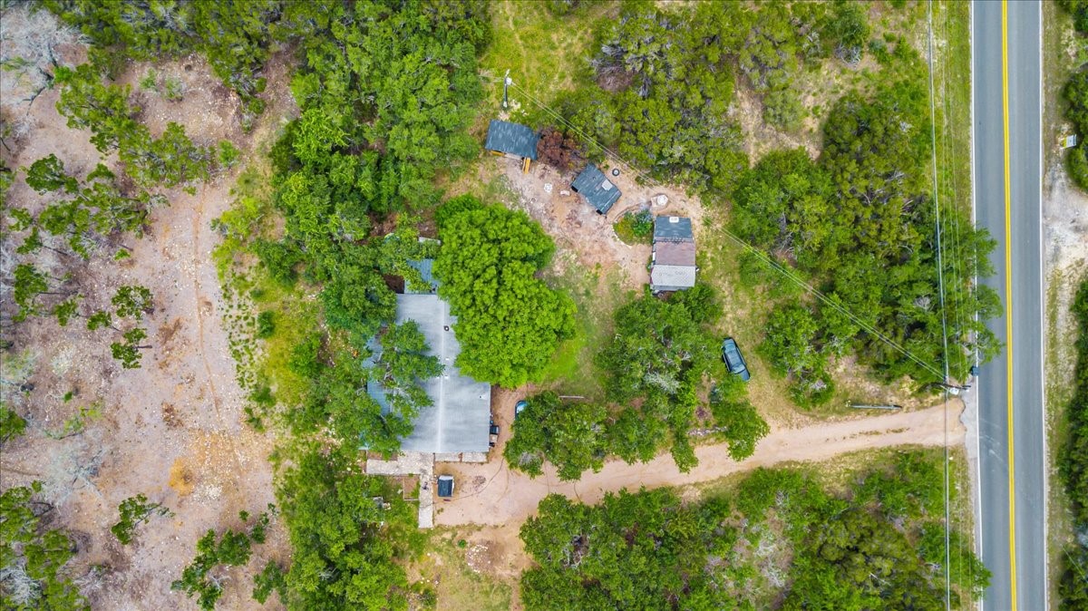 4519 Crawford Road Spicewood, TX 78669 - Photo 8 of 9 An aerial perspective reveals a secluded residence nestled among a vibrant, natural landscape adjacent to a quiet roadway.
