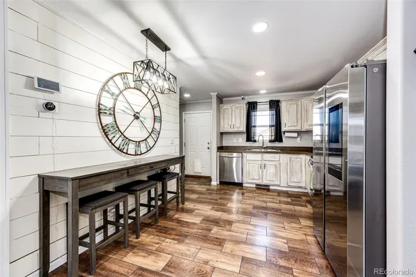 a kitchen with stainless steel appliances kitchen island granite countertop a stove a refrigerator a dining table and chairs with wooden floor