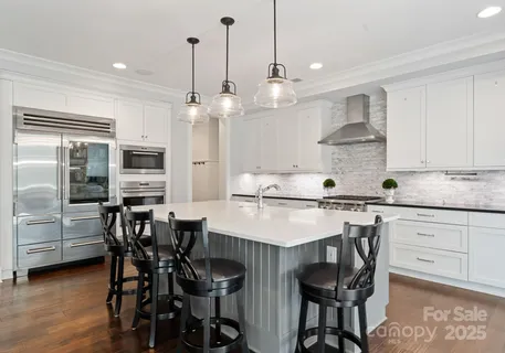 a kitchen with stainless steel appliances kitchen island a dining table chairs and sink