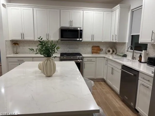 a kitchen with stainless steel appliances a sink a stove a microwave a sink a refrigerator and cabinets