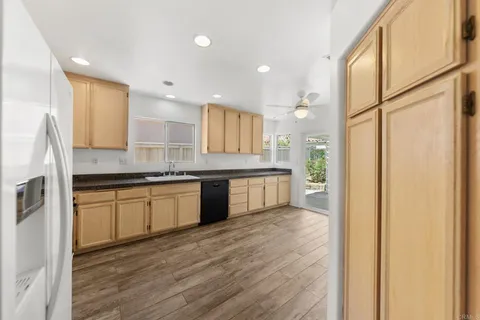 a kitchen with a sink wooden floor cabinets and a large window