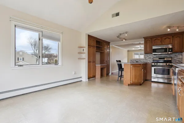 a view of kitchen with stainless steel appliances wooden floor and window