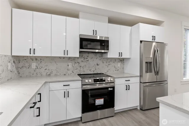 a kitchen with cabinets stainless steel appliances and wooden floor