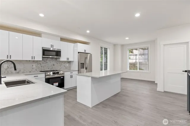 a large kitchen with stainless steel appliances granite countertop a stove a sink dishwasher and a refrigerator with wooden floor