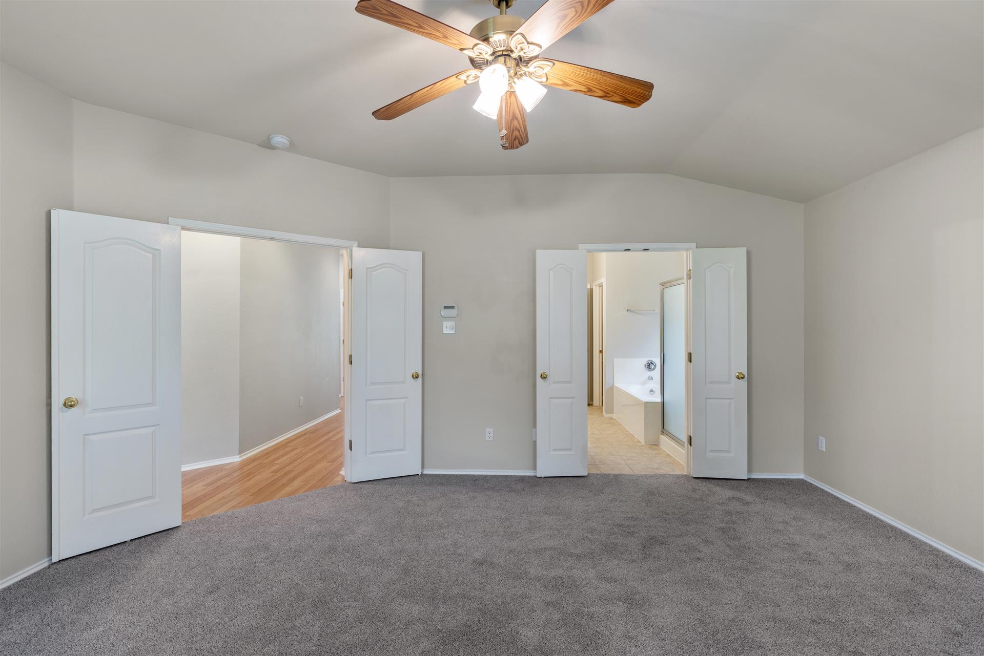 4725 Tello Path Austin, TX 78749 - Photo 18 of 34 A spacious bedroom with vaulted ceilings, featuring a classic ceiling fan and plush carpeting, leading into an en-suite bath.