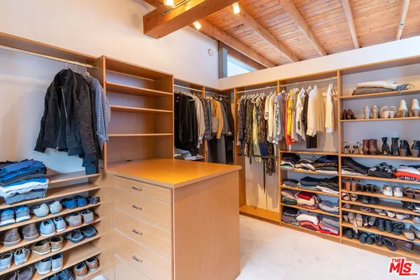 a view of walk in closet with clothes and shoes