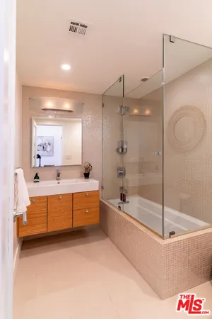 a bathroom with a tub a sink and a large mirror