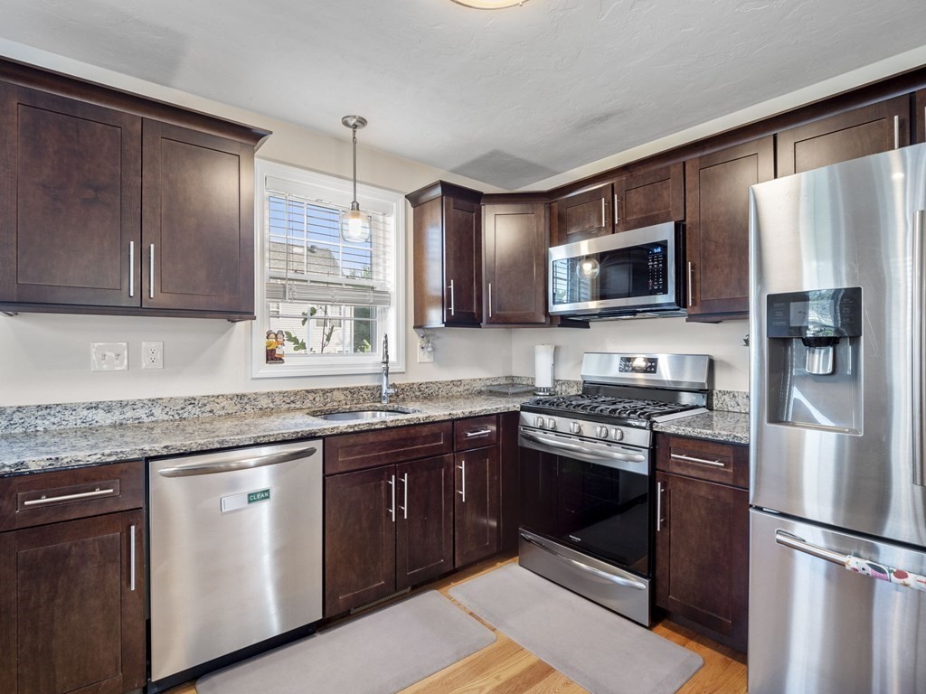 27 Riley Road, Unit 27 Tyngsborough, MA 01879 - Photo 12 of 37 a kitchen with stainless steel appliances granite countertop a stove top oven a sink dishwasher a refrigerator and a microwave oven with cabinets