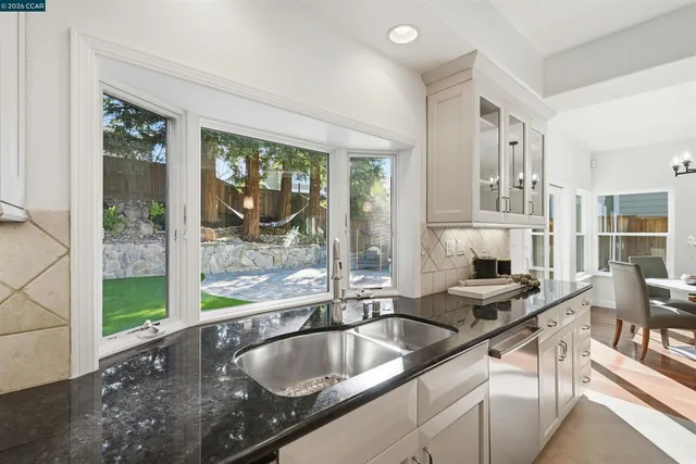 a very nice looking kitchen with granite countertop a sink and a large window