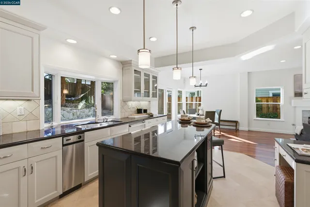 a kitchen with granite countertop a stove a sink a kitchen island with chairs and wooden floor