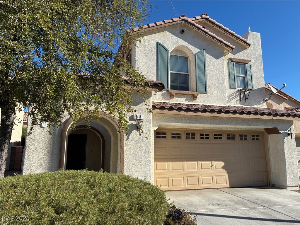 Mediterranean / spanish-style home with stucco siding, an attached garage, and concrete driveway