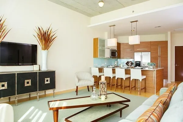 a living room with stainless steel appliances kitchen island granite countertop a couch and a flat screen tv