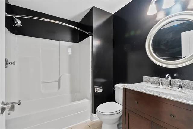a bathroom with a granite countertop bathtub sink vanity mirror and toilet