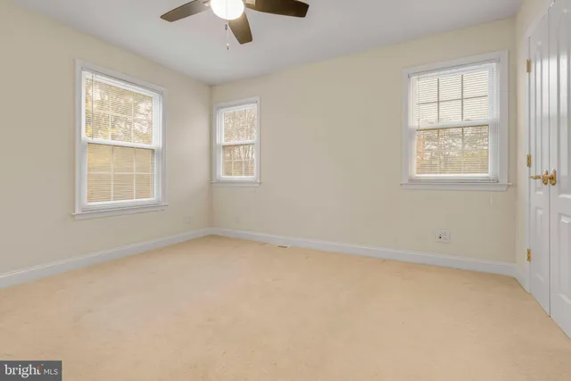an empty room with windows and chandelier fan