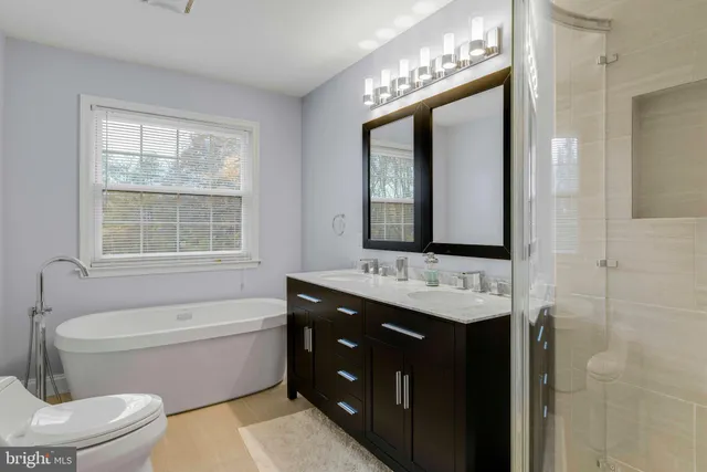 a bathroom with a double vanity sink toilet mirror and bathtub