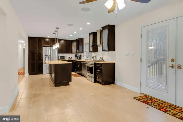 a kitchen with stainless steel appliances granite countertop a stove top oven a sink and a refrigerator
