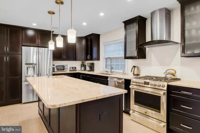 a kitchen with stainless steel appliances kitchen island a stove a sink a refrigerator and cabinets