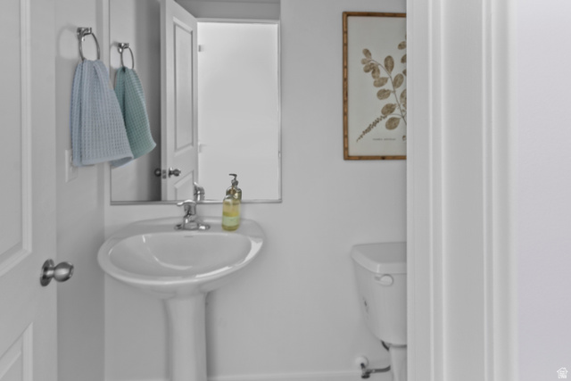 1264 West 500 South, Unit 320 Logan, UT 84321 - Photo 39 of 39 Pedestal sink with chrome faucet, mirror, and toilet, all set against white walls