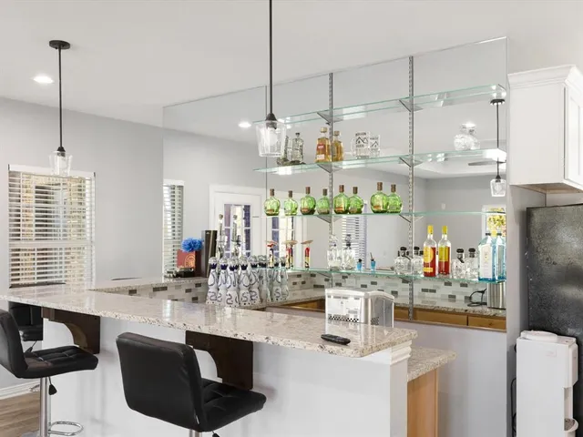 a kitchen with stainless steel appliances kitchen island granite countertop a refrigerator a sink dishwasher a oven and a dining table with the kitchen view