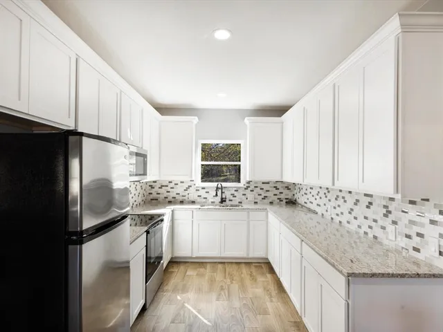 a kitchen with granite countertop a sink stainless steel appliances and cabinets