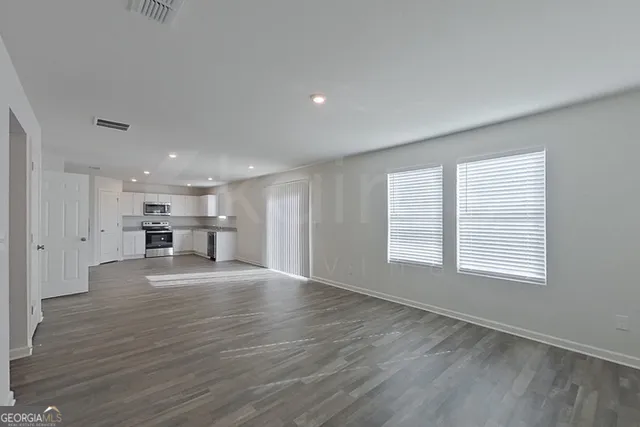 a view of an empty room with a window and wooden floor
