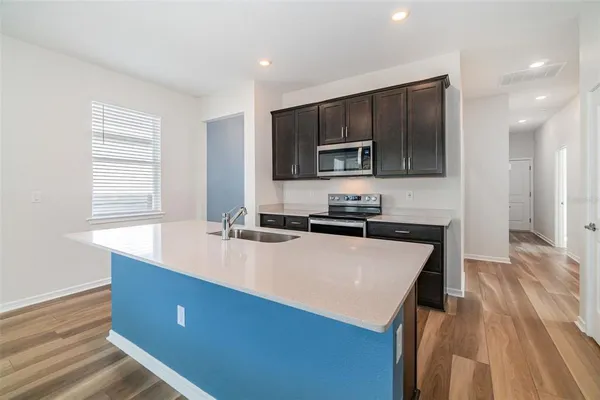 a large kitchen with kitchen island a sink dishwasher a stove and a microwave oven with wooden floor