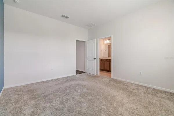 an empty room with an entryway and kitchen space