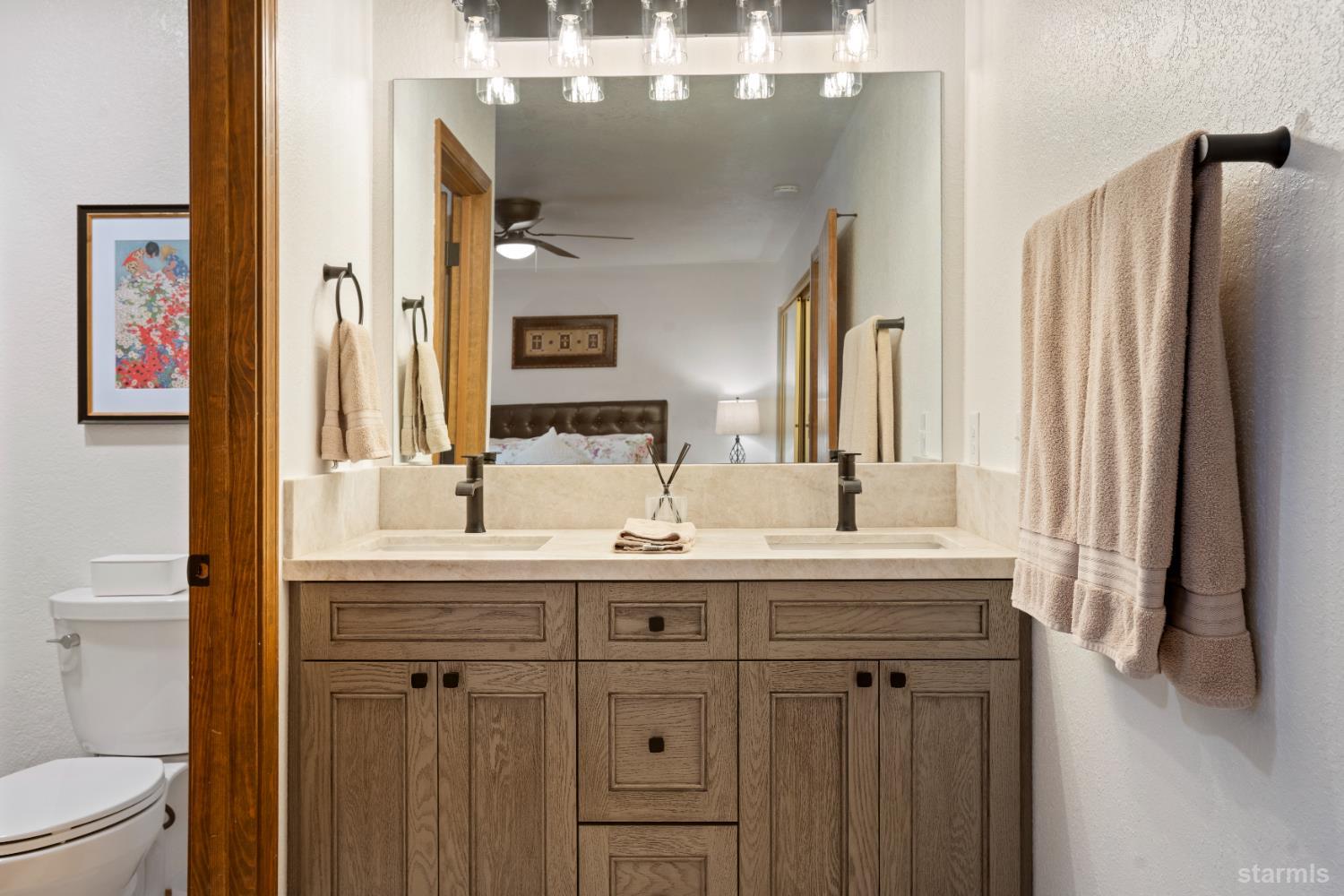 1408 Pebble Beach Road South Lake Tahoe, CA 96150 - Photo 26 of 34 a bathroom with a granite countertop sink a toilet a mirror and shower