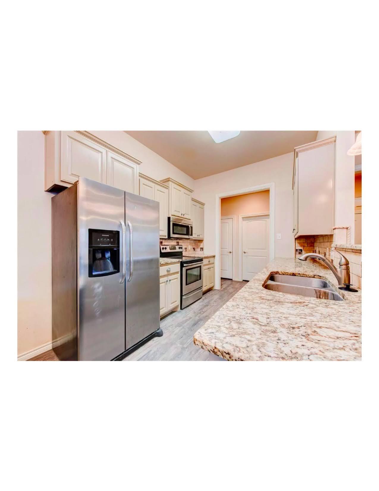 10103 Waco Avenue Lubbock, TX 79423 - Photo 9 of 14 a kitchen with stainless steel appliances kitchen island granite countertop a refrigerator and a sink
