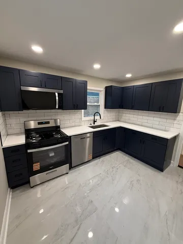 a kitchen with stainless steel appliances kitchen island granite countertop a sink and a stove top oven with wooden floor