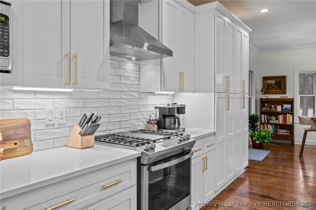 30181 East Lake Road Wagram, NC 28396 - Photo 17 of 38 a kitchen with stainless steel appliances a stove a white cabinets and a wooden floor