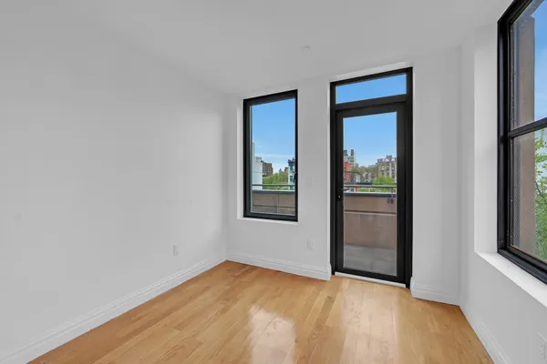 a view of an empty room with window and wooden floor