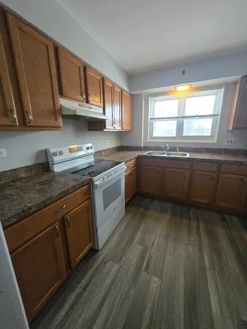 a kitchen with stainless steel appliances granite countertop wooden cabinets a sink and dishwasher a stove with wooden floor