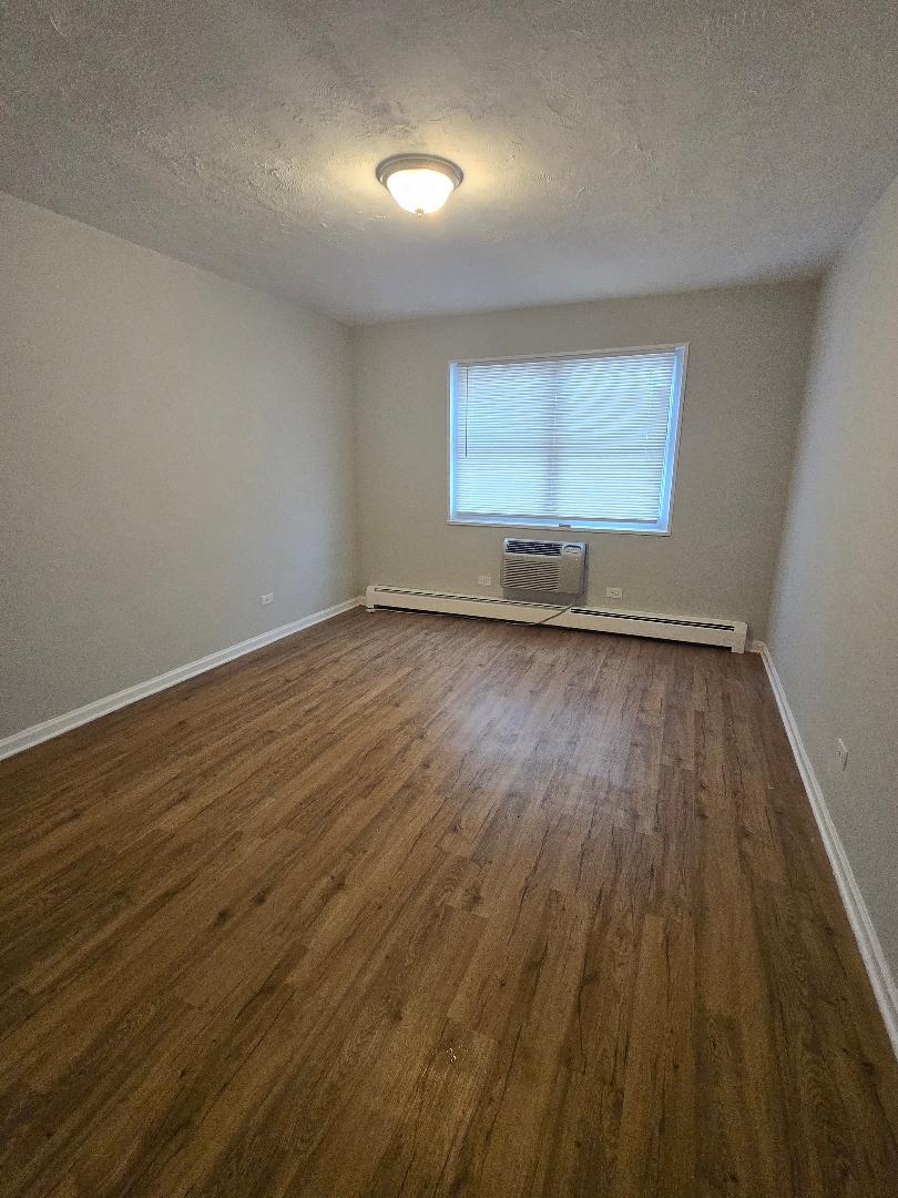 570 Princeton Street, Unit D2W Des Plaines, IL 60016 - Photo 7 of 10 an empty room with wooden floor and windows