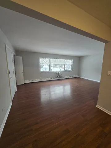 a view of empty room with window and wooden floor