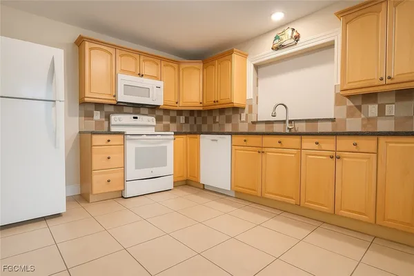 a kitchen with white cabinets appliances and a window