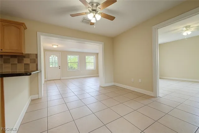 a view of an empty room with window and chandelier fan
