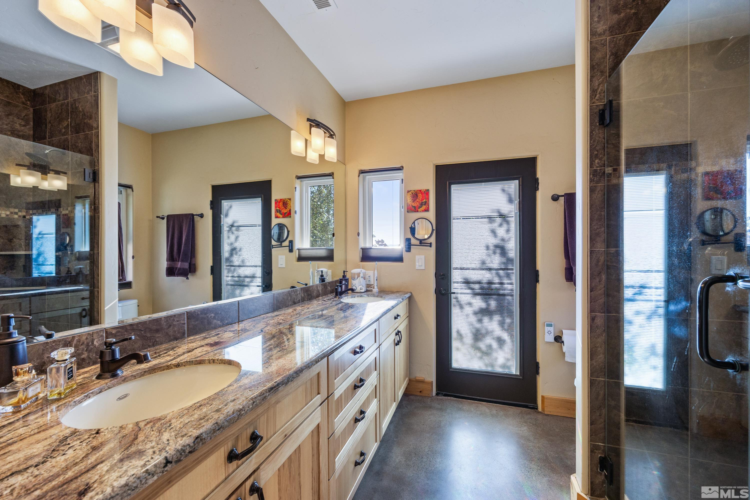 5745 Carl Drive Reno, NV 89511 - Photo 11 of 40 a bathroom with a granite countertop double vanity sink a mirror and a shower
