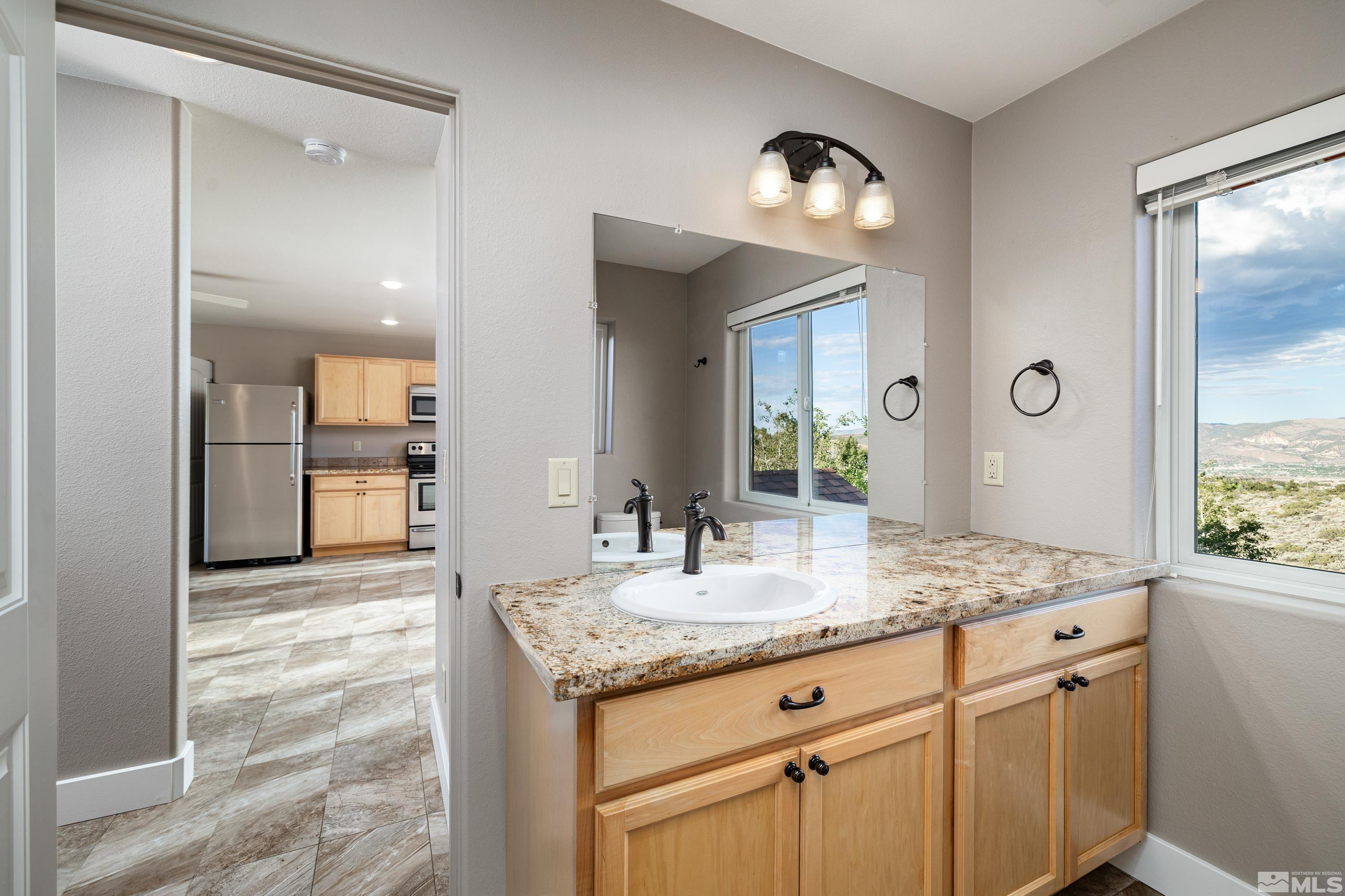 5745 Carl Drive Reno, NV 89511 - Photo 29 of 40 a bathroom with a granite countertop sink and a mirror