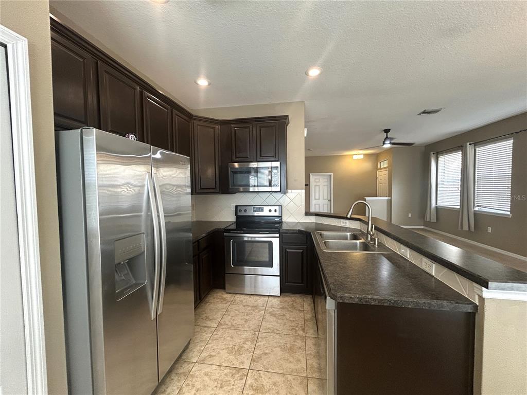 9036 Moonlit Meadows Loop Riverview, FL 33578 - Photo 9 of 20 a kitchen with stainless steel appliances granite countertop a refrigerator a sink a stove and island
